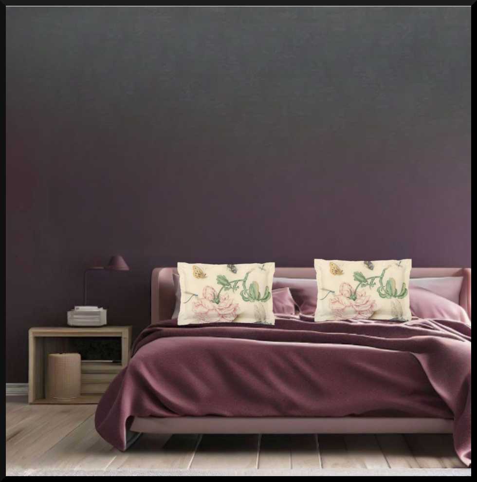 A micro fibre Pillow sham with 2 inch flange. A botanical print of butterflies , a bee and blue dragonflies. A large pink downturned rose is at the centre of the print.. a pair pictured on a bed with eggplant purple velvet bedding. A dark grey wall and a bedside table to the left of the bed