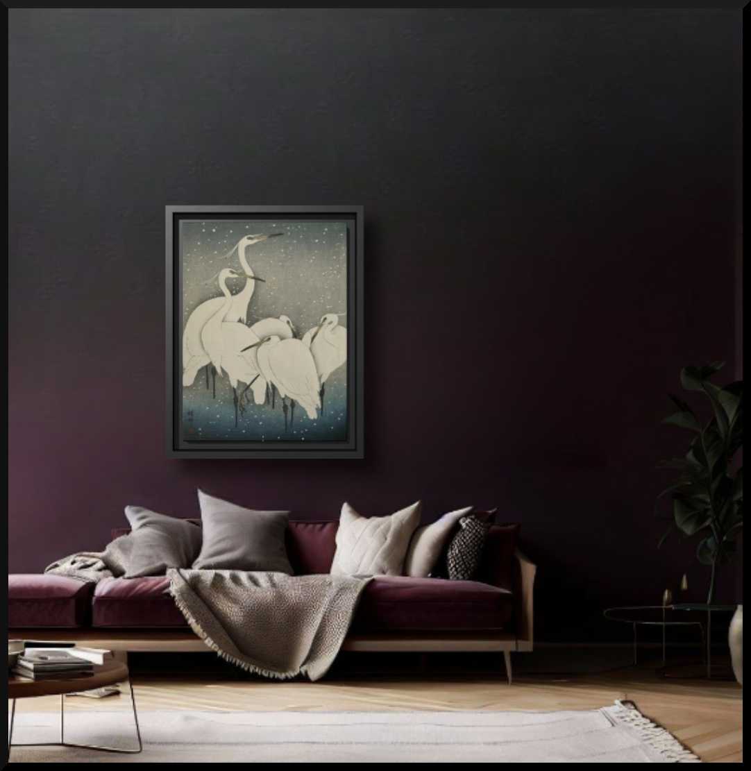 'Cranes in the Snow' Matte Canvas Museum Art Print, Black Wooden Frame 9 x 12 inches shown in a larger size on a dark grey wall above an eggplant coloured velvet sofa laden with pillows and a beige throw blanket, sophisticated living room setting