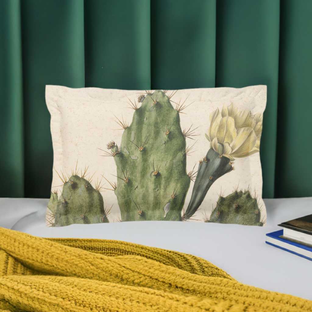 Pillow sham with 2 inch flange - micro fibre - Cactus with yellow flower on cream background - Pictured in front of a green velvet headboard on a white duvet cover behind a yellow knit blanket lying on the bed