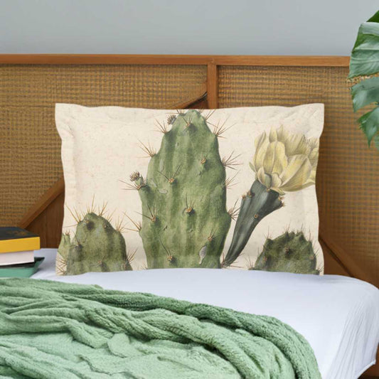 Pillow sham with 2 inch flange - micro fibre - Cactus with yellow flower on cream background - Pictured in front of a wooden headboard on a white duvet cover behind a pale green cable knit blanket lying on the bed